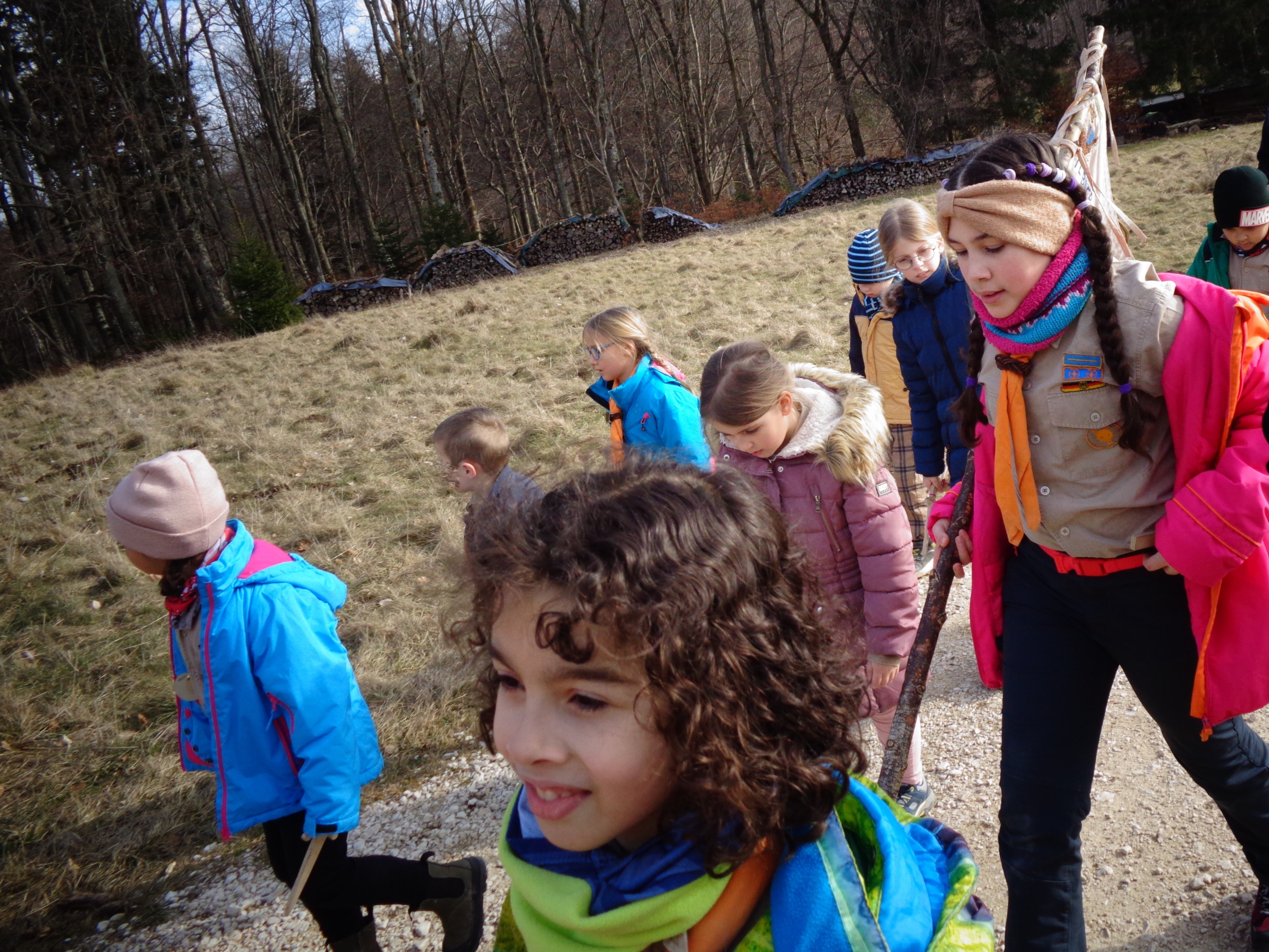 Eine Gruppe Wölflinge läuft auf einen Weg am Waldrand entlang