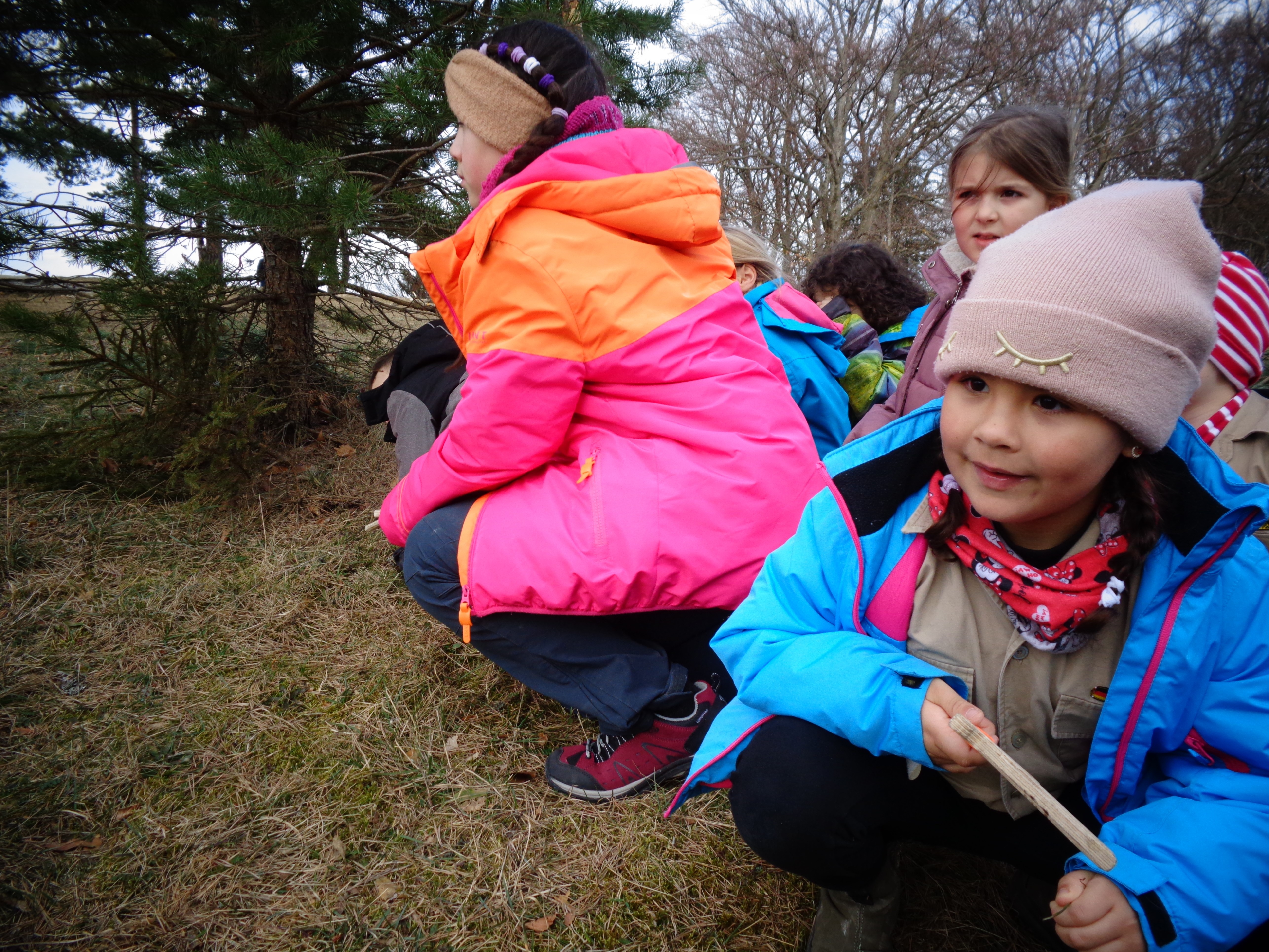 Kinder sitzen hinter einem Busch im Versteck