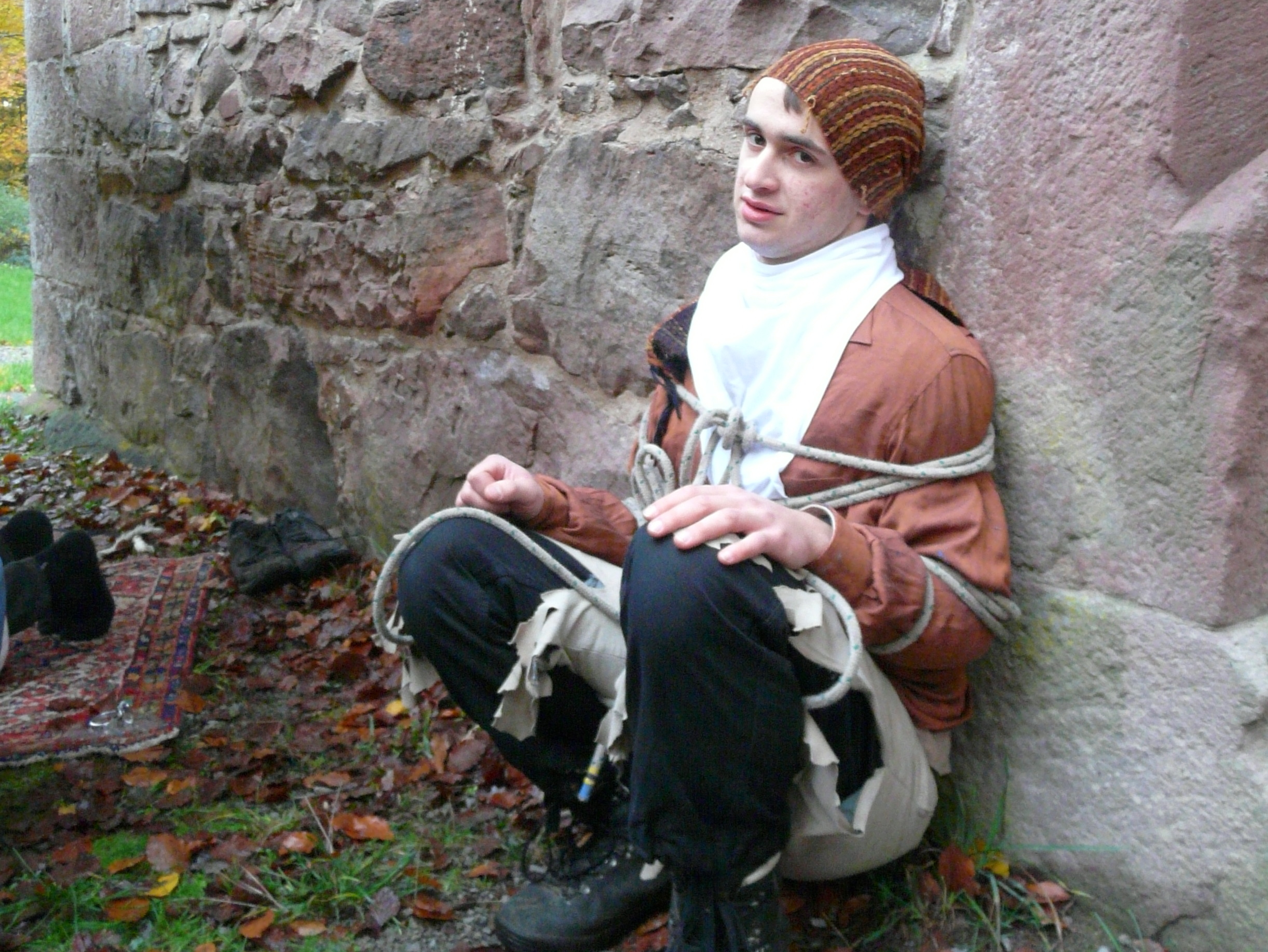 Der gefesselte Dieb sitzt an der Mauer.