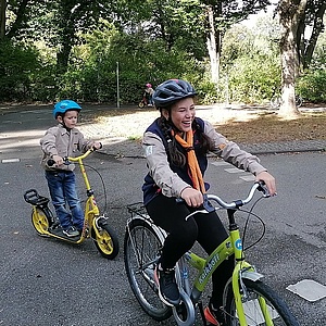 Zwei Wölflinge fahren lachend auf dem Fahrrad um die Kurve