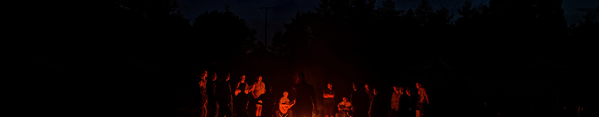 Im Dunkeln sitzen die Pfadfinder um ein Feuer und singen