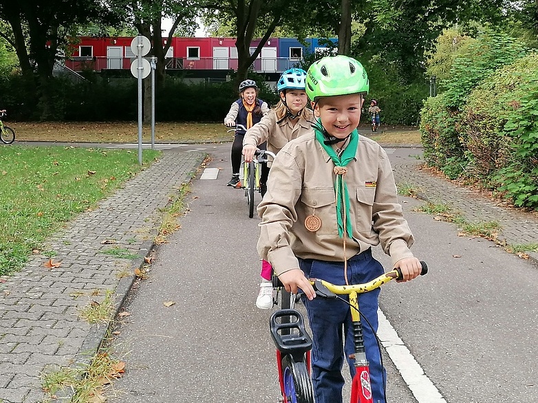 Einige Kinder fahren in einer Reihe lachend auf die Kamera zu