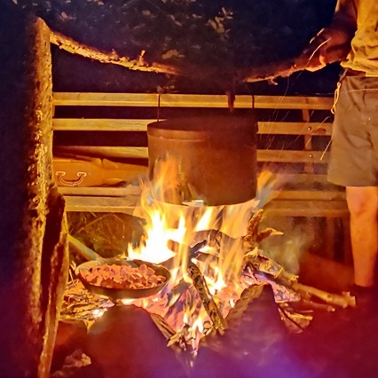 Ein Topf hängt über dem Feuer am Abend