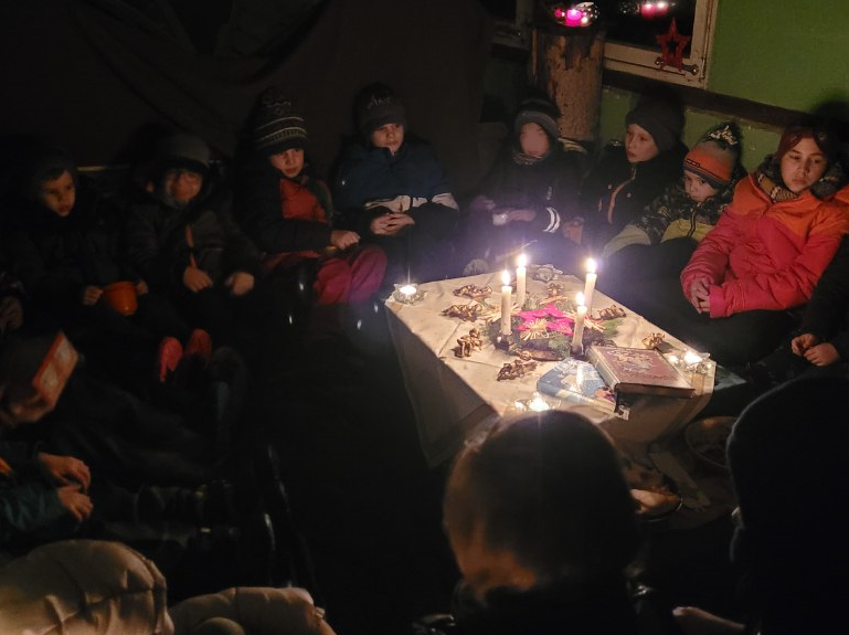 Eng gedrängt sitzen die Kinder in der Hütte um den Gabentisch