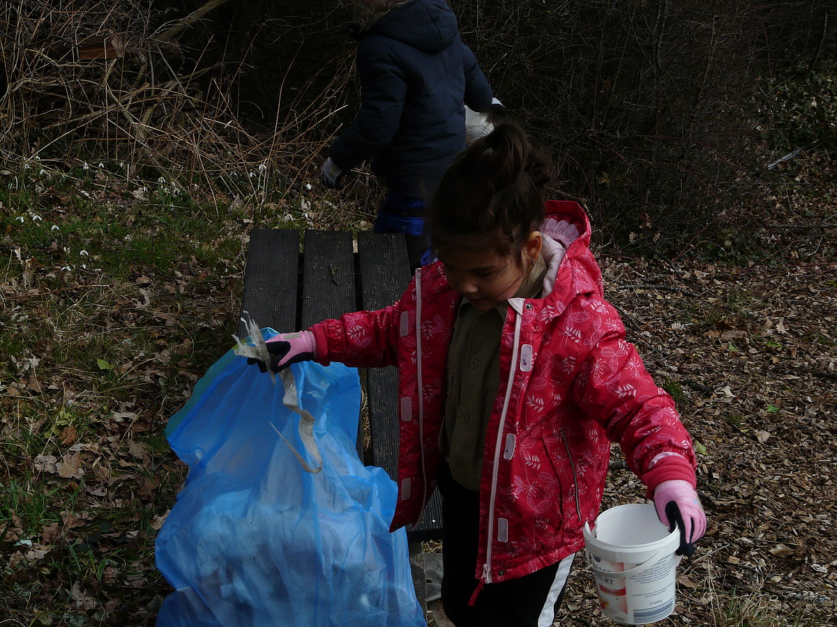 Eine Pfadfinderin sammelt Müll in einen Müllbeutel